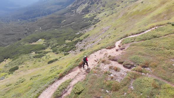 Aerial View of a Traveler with Backpack Climbing Along Mountain Slope. Epic Shot