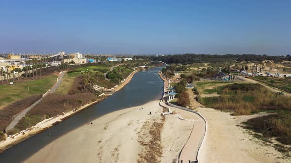 Hadera Park flying in over river mouth, sandbank and modern bridge to the Hadera Water Park, located