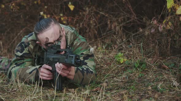 Soldier Lies on a Forest Path Aims with Rifle on an Object and Ready to Shoot