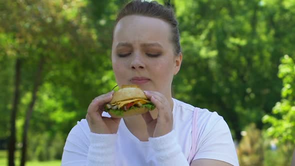 Sad Woman Eating Burger With Disgust, Lack of Willpower, Fast Food Addiction