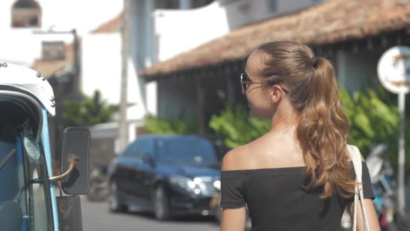 Lady Enjoys Vacation Walking Along Street Past Motorbikes