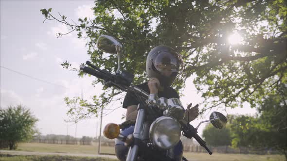 A Biker Sitting on His Motorcycle Takes Off His Helmet and Smiles for the Camera