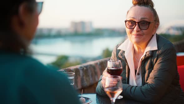Mature Woman in Glasses Sitting in a Cafe with Her Daughter and Drinking Wine