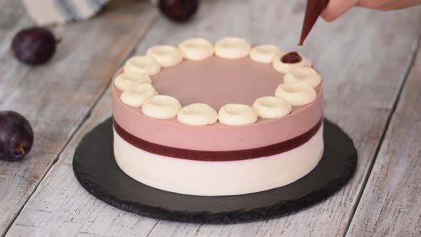 Pastry chef decorated a delicious plum mousse cake with jam