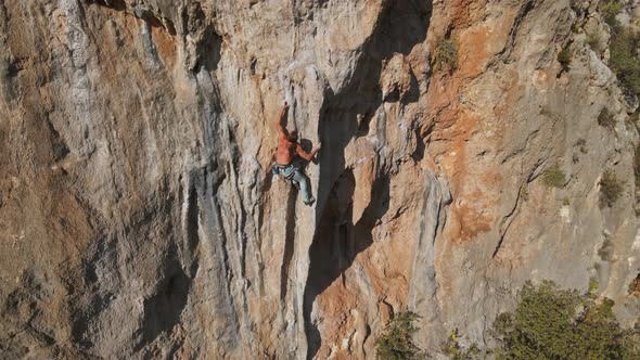 Aerial Drone Footage of Strong Muscular Man Climbing Challenging Rock Climbing Route on Vertical