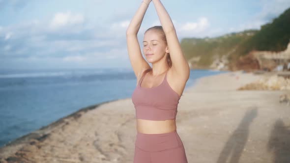 Portrait of Woman Practices Yoga Concentrates on Breathing at Beach Slow Motion