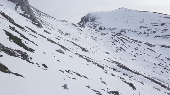 Flying towards top of snow-capped mountains. Aerial forward