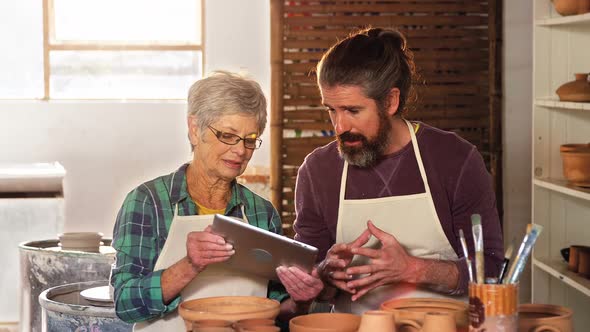 Male and female potter using digital tablet