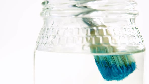 Close-up of paintbrush with blue paint being washed in water