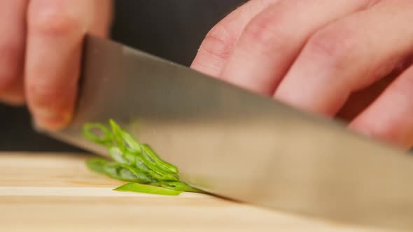 Professional Chef Cutting Green Onion on Wooden Cutting Board Closeup