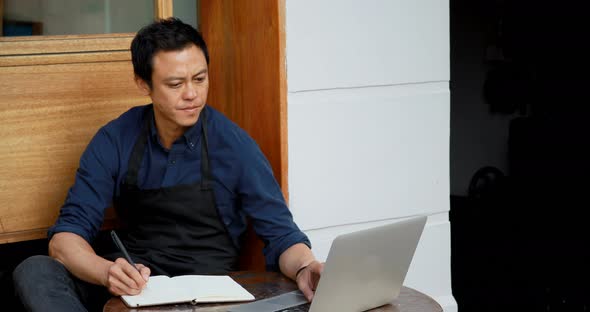 Waiter using laptop and writing on notepad 4k