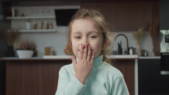 Portrait of Adorable Happy Preschool Age Girl Blowing a Kiss and Smiling Indoors