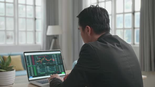 Asian Businessman Looking At Stock Chart On The Computer While Working At Home