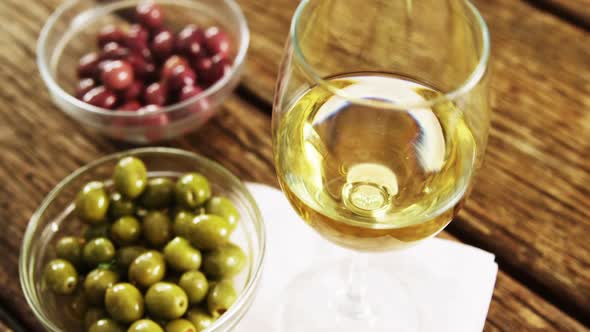 Wine served with green and red olives on wooden table