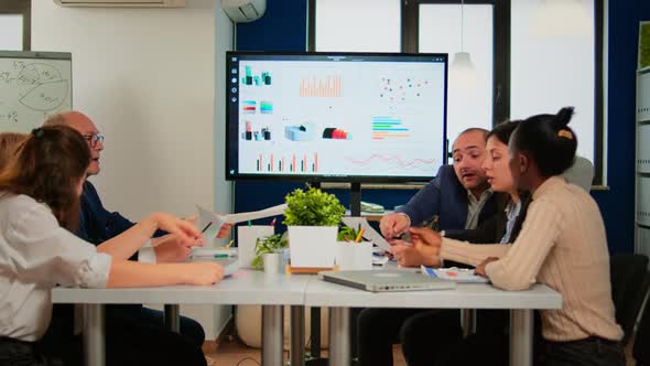 Man Leader Pointing at Digital Interactive Whiteboard Sitting at Brainstorming Table