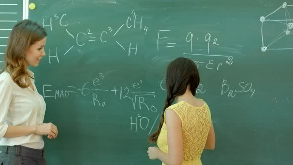 Student Writing Chemical Symbol on Blackboard