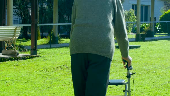 Elderly Man Using His Walker Along the Hospital Rehab Facility Garden