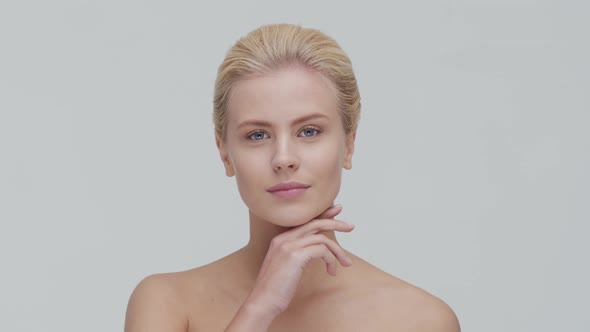 Studio portrait of young, beautiful and natural blond woman applying skin care cream. F