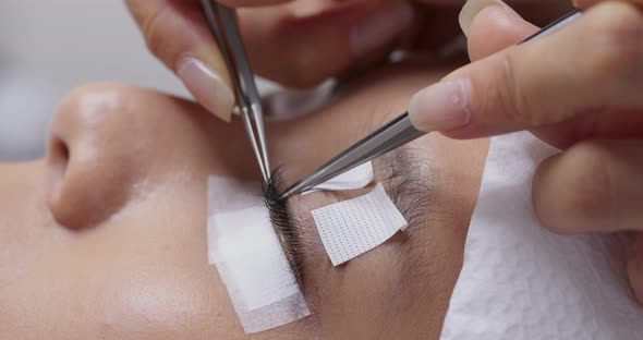 Female having eye lash extension in beauty salon