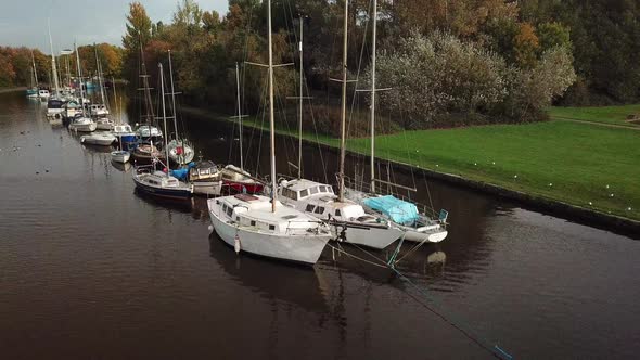 Geese landing on water as slow panning rotation around sail boats on canal.