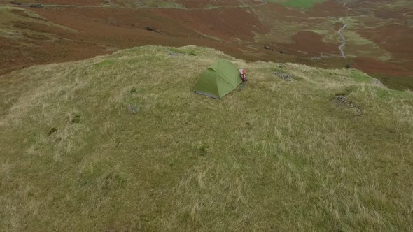 Hiker aerial view hiking in the hills and sleeping in a tent