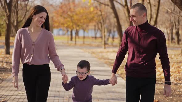 Boy Walking with His Parents Holding Hands