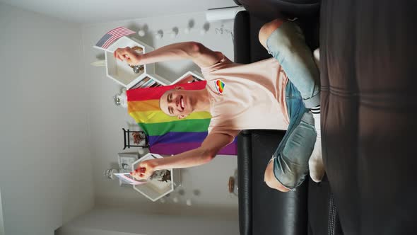 American Gay Activist Fighting for Queer People Rights Waving USA Flag While Sitting on a Sofa