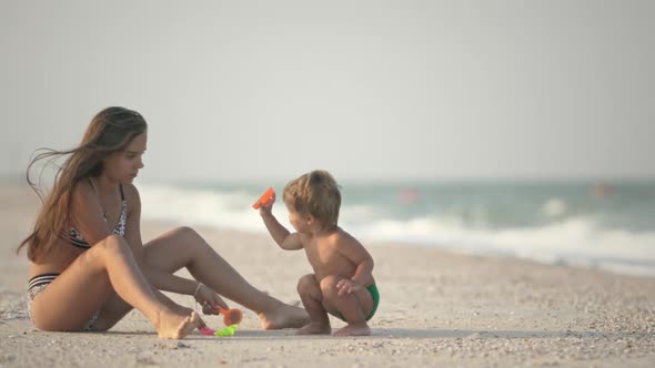 Older Sister Playing with Younger Brother Aground Near the Shore on Summer Vacation