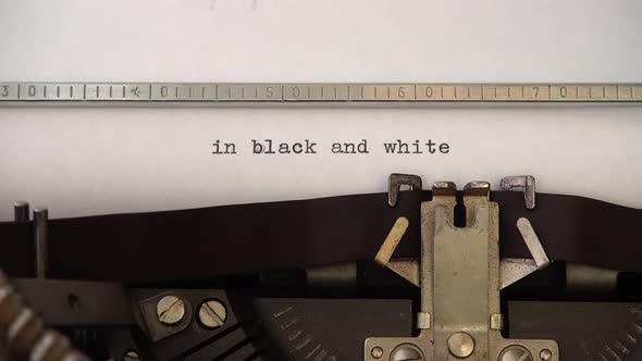Typing phrase in black and white on retro typewriter. Close up.