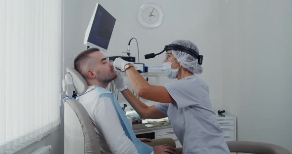 A Otorhinolaryngologist Examines the Sinuses of a Patient Using a Medical Mirror