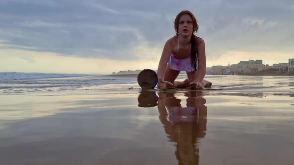 Low angle of adorable caucasian little girl playing with bucket and sand on beach. Slow-motion