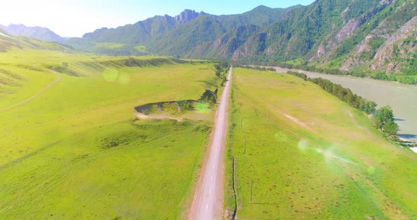 Aerial Rural Mountain Road and Meadow at Sunny Summer Morning. Asphalt Highway and River.