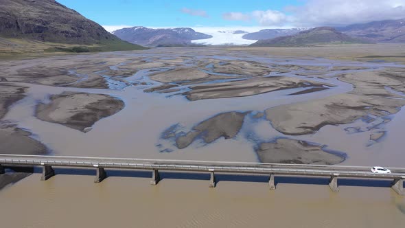 Aerial View of A Car Crossing a Bridge Over a Glacial River