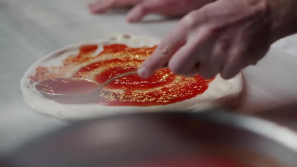 Spreading Tomato Sauce on Pizza Dough