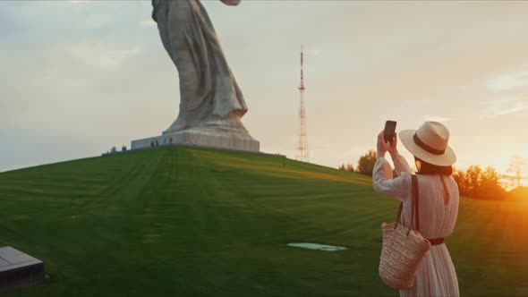 A young tourist taking a photo of a monument on a smartphone in Volgograd