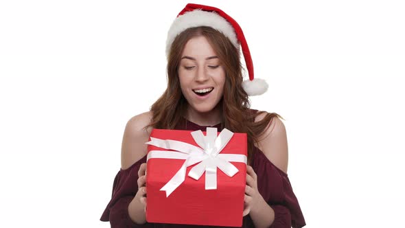 Portrait of Amusing Woman in Santa Claus Red Hat Being Puzzled Expressing Curiosity While Trying to