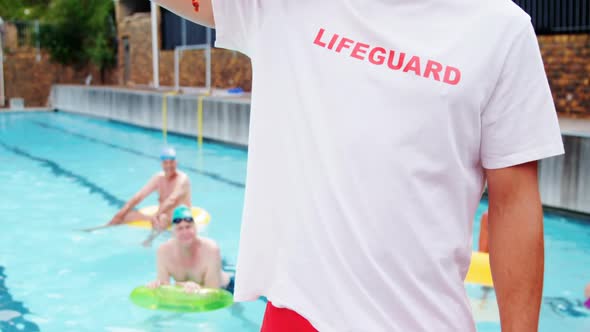 Swim coach standing inflatable floater near poolside