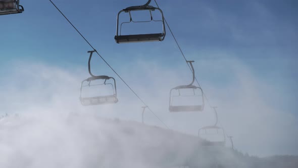 Empty Ski Lifts Against Blue Sky in Motion Artificial Snow Sprayed By Snow Cannon in Sunny Winter