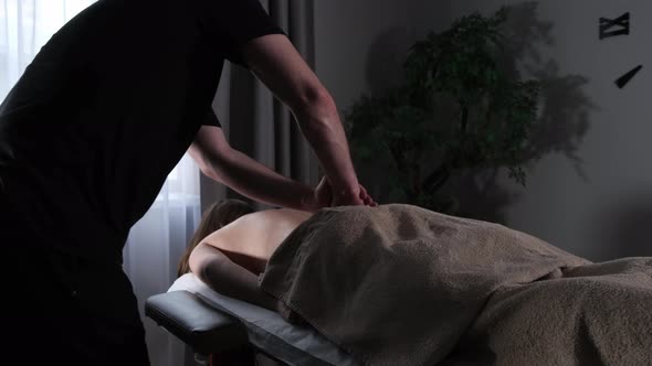 Masseur in a Black Tshirt Massaging His Back