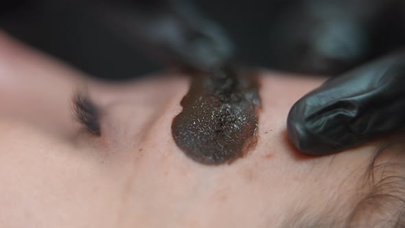 Finger in Gloves Spreading Ink on Eyebrow Skin of Client in Beauty Salon