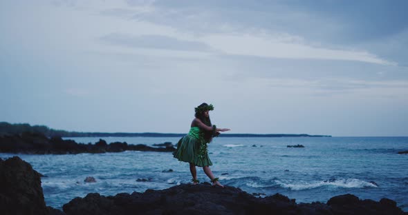 Woman performing traditional Hawaiian hula by the ocean alt