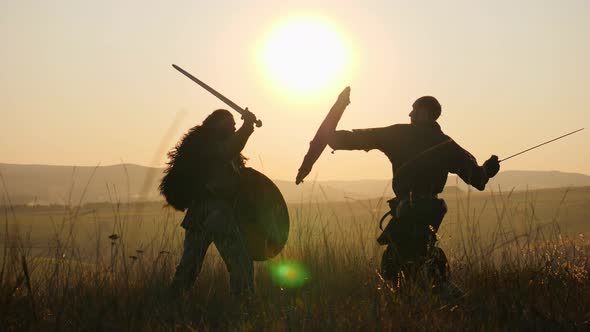 Silhouettes of Warriors Viking Are Fighting with Swords and Shields. Contre-jour