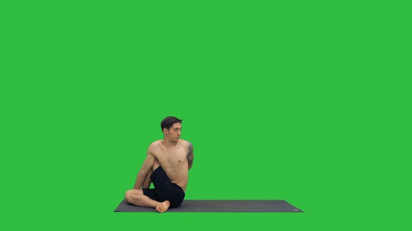 Man practicing yoga stretching torso on a Green Screen,