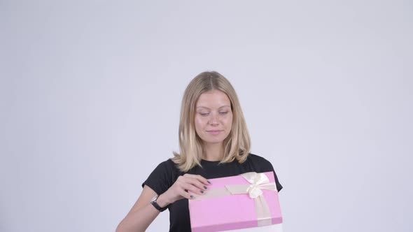 Young Happy Blonde Woman Opening Gift Box and Looking Surprised
