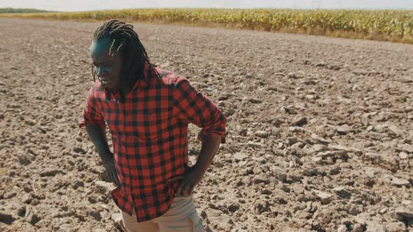 Young African Farmer Standing on the Agricultural Plowed Land and Nodding Head for Approval