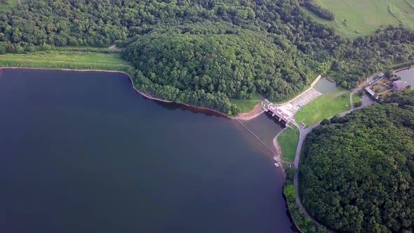 Drone View of Smooth Water and a Dam Surrounded By Green Hills