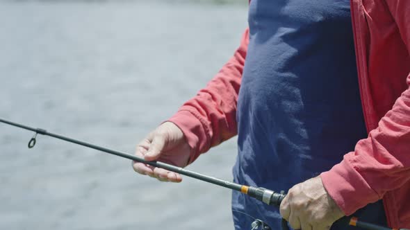 Slow Motion From Fishing Rod To Senior Man Wearing Face Mask While Fishing on Lake