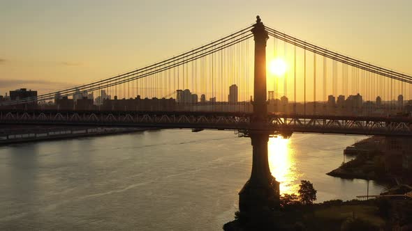 A  view of the East River at sunrise. The drone camera dolly out and boom up from the Manhattan Brid