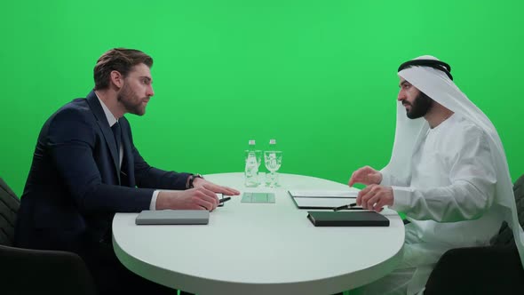 An Arab Man in a White Kandura Sign Financial Documents with a Partner Businessman in a Suit While