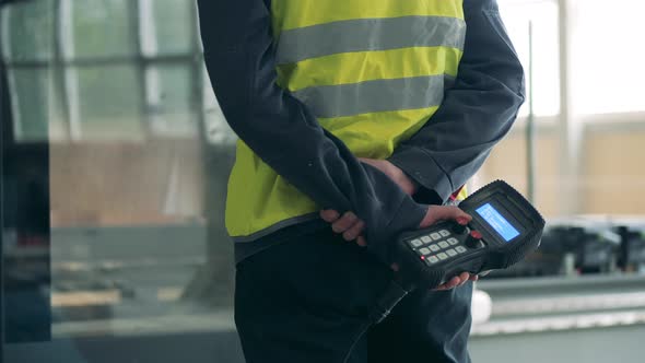 Industrial Worker Is Holding an Electronic Machine Behind His Back